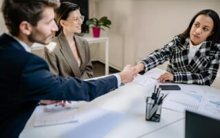 HR professional and employees meeting and shaking hands during a workplace discussion, representing efforts to bridge the employee–HR relationship gap